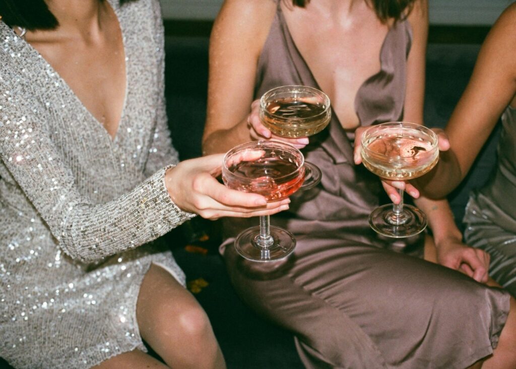 Tre personer i festklänningar skålar i champagne